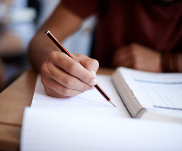 Closeup shot of a young man writing on a note pad